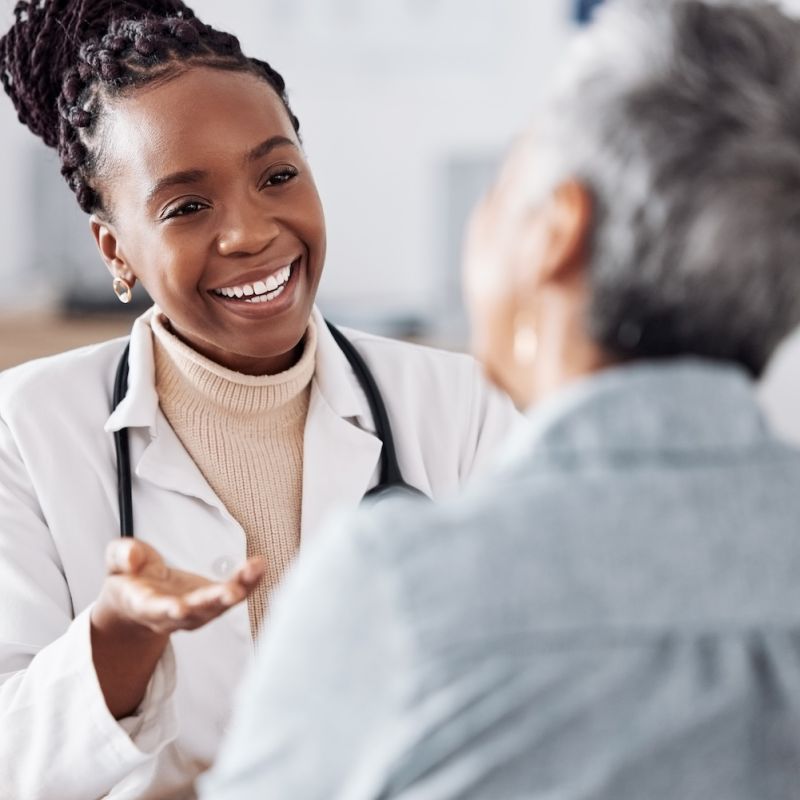 Smiling female doctor talking with a senior patient in a medical office.