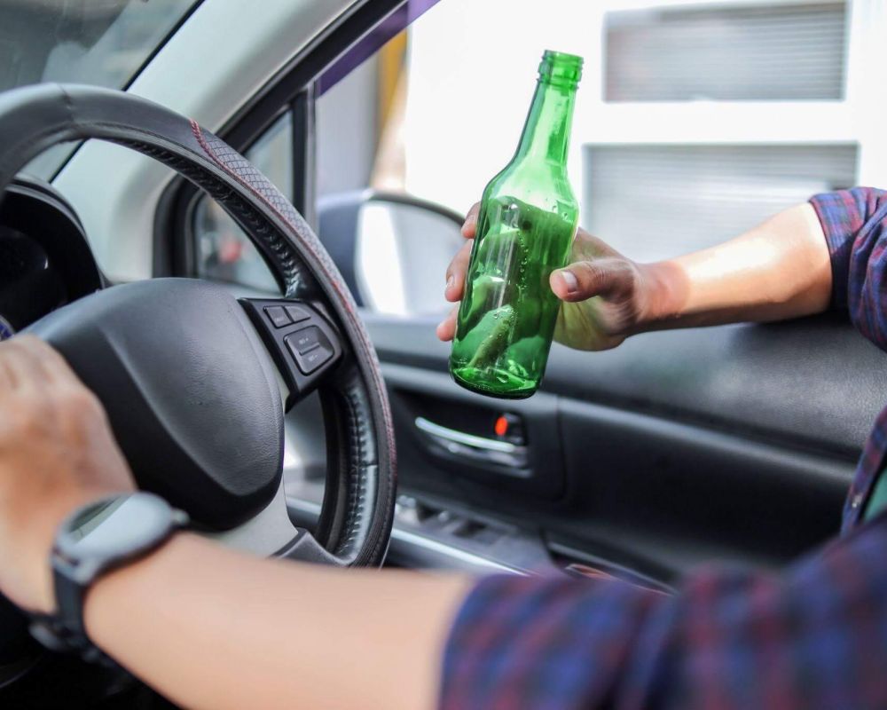 Person driving car while holding a bottle, relevant