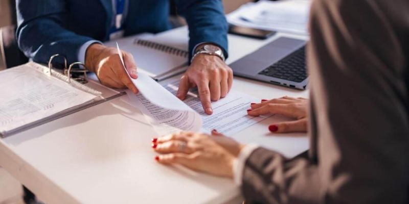 Two people reviewing papers and laptops for LLC dissolution in