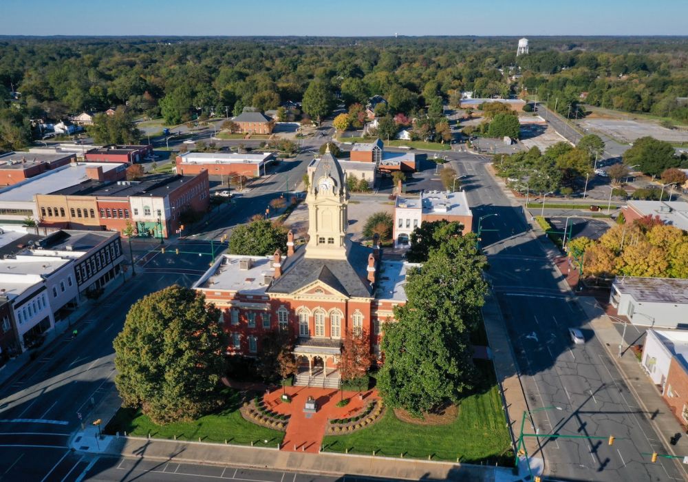 Aerial view of a historic courthouse surrounded by trees and buildings in a small town setting.