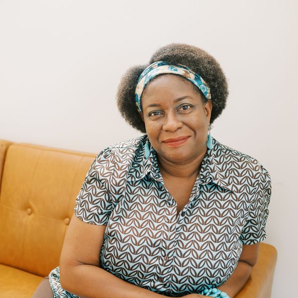 Tonia Gray Adams sitting on a couch wearing a patterned shirt and blue headband.