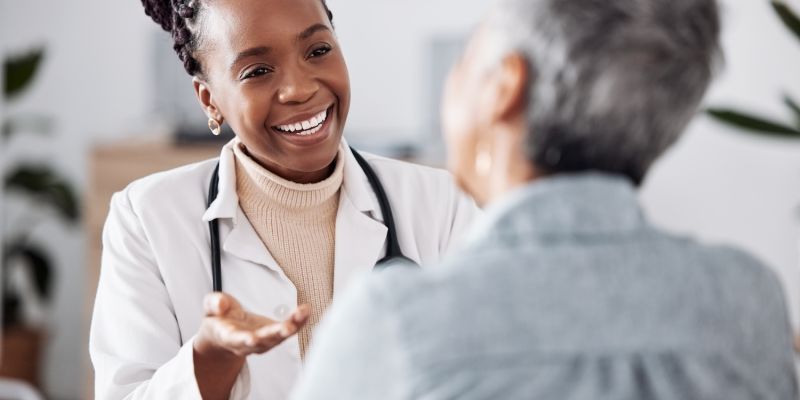 Smiling female doctor talking with a senior patient in a medical office.