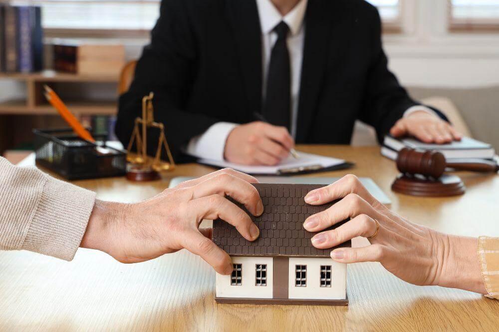 a couple of people sitting at a table with a model house