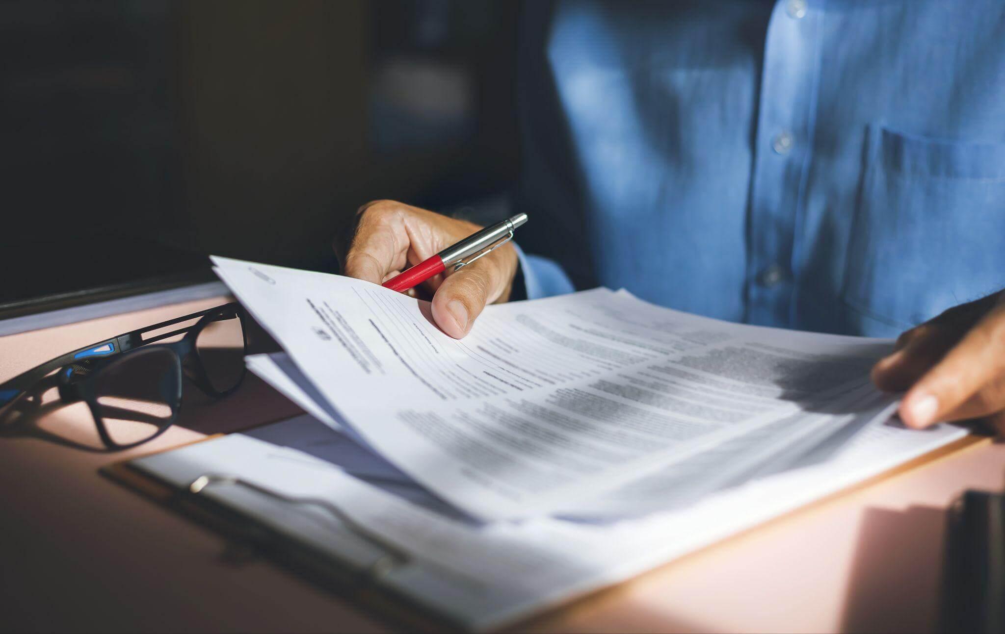 a person is holding a pen and writing on a piece of paper