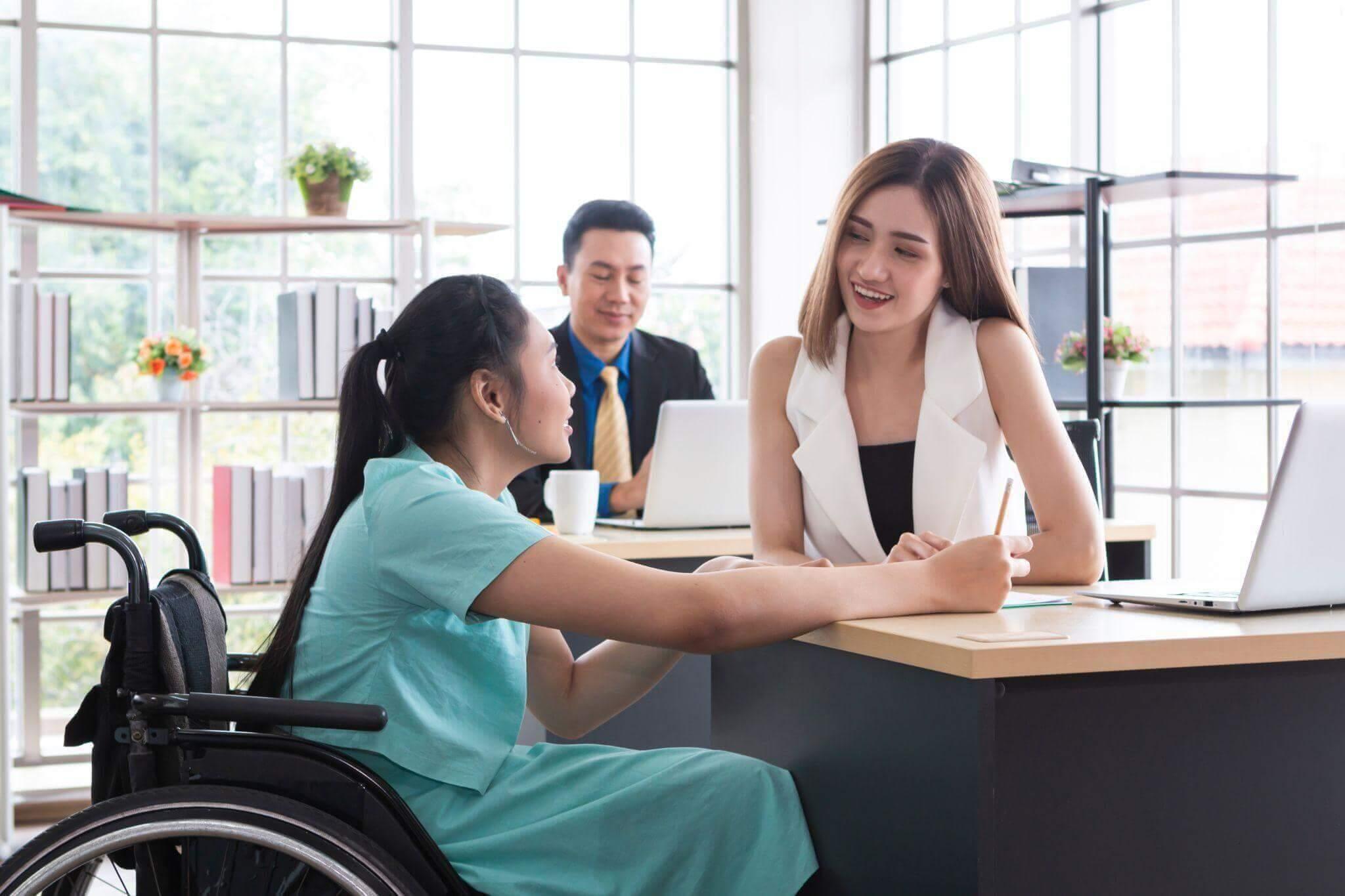 a woman in a wheelchair shaking hands with another woman