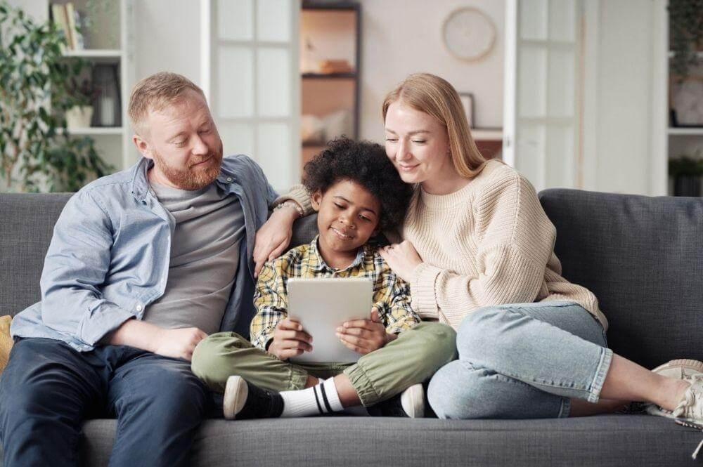 Family on couch viewing tablet, likely sharing a positive