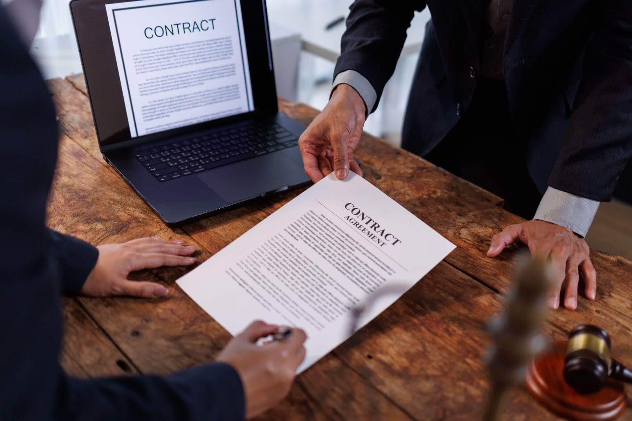 Two people with a laptop discussing a business contract with